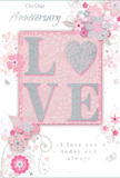 This anniversary card appears like a gentle celebration of love, its pastel pinks and silvery greys combining to create the same feeling of calm intimacy you might find beside the river in Weybridge. The focal point is the word LOVE, beautifully set in raised, glitter-kissed letters so that the surface catches the light with a subtle shimmer. The glitter is soft rather than bold, blending pearly white, blush, and silver tones that echo the quiet elegance of a freshly arranged bouquet from Flower Delivery Weybridge. The O is cleverly shaped into a heart, filled with slightly denser silver texture, making it the sparkling centre of the composition. Around this word, delicate blooms unfurl in shades of blush pink and mauve, their outlines fine and flowing, reminiscent of watercolour petals outlined in ink. These flowers are intertwined with slender vines and curling tendrils that meander across the card, adding lightness and a sense of movement, like stems gently turning as a florist adjusts an arrangement. Small flourishes-suggestions of petals in mid-fall, tiny swirls, and faint butterfly silhouettes-are scattered among the flowers, offering a whisper of playfulness without disrupting the serene design. The background is a soft, even pink that allows the silver and white highlights to glow subtly. At the top, the phrase On Our Anniversary is written in delicate, sloping script, while below, I love you today and always rests calmly in matching lettering. Together, the elements create a keepsake that feels both intimate and refined, a paper bouquet perfectly suited to honour an enduring love story in Weybridge.